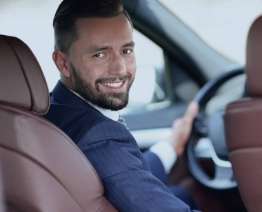 bir araba direksiyon başında oturan ve kameraya bakarak işadamı