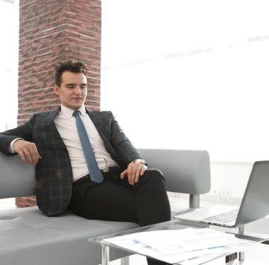 Genç işadamı ofiste dizüstü bilgisayarla çalışıyor.