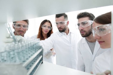 arka plan görüntüsü sıvı cam tüp içinde eğitim microbiologists oluşan bir gruptur.