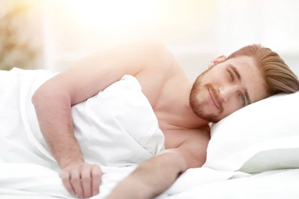 Happy man, falling asleep in a comfortable bed — Stock Photo, Image