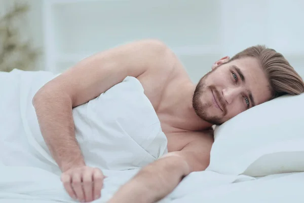 Happy man, falling asleep in a comfortable bed — Stock Photo, Image