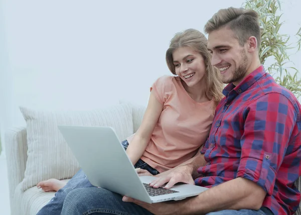 Sorrindo jovem casal com laptop sentado no sofá — Fotografia de Stock