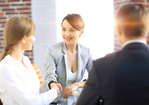 рукопожатие управляющего и клиента, сидящего за столом
