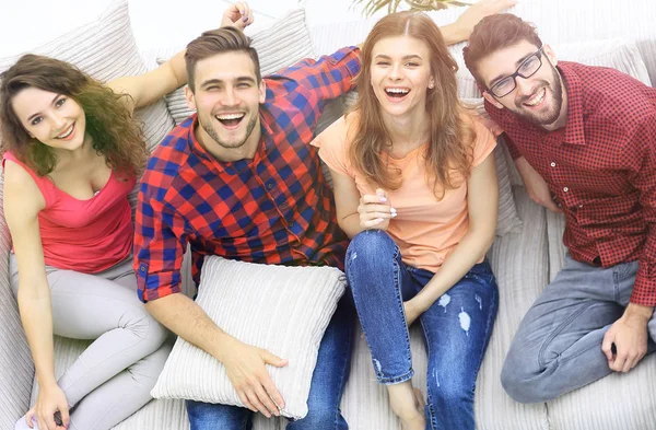 Cuatro amigos felices riendo mientras están sentados en el sofá —  Fotos de Stock