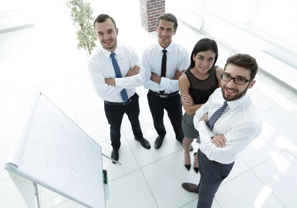 Бизнес-команда, стоящая рядом с бланком флипчарта — стоковое фото