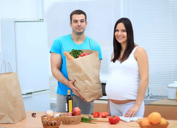 Husband and pregnant wife are considering the products in the package — Stock Photo, Image