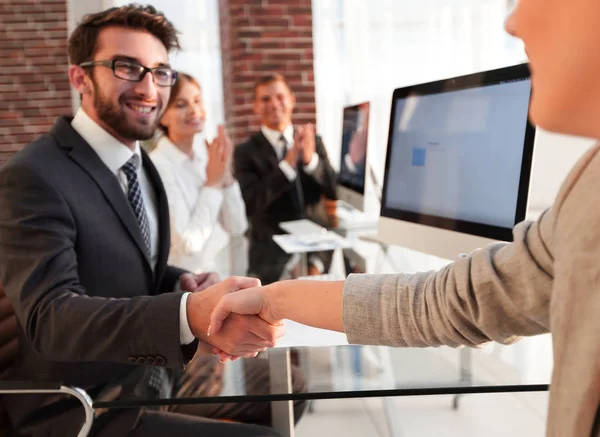 Empresário apertando as mãos com um parceiro de negócios sentado perto de seu desktop — Fotografia de Stock