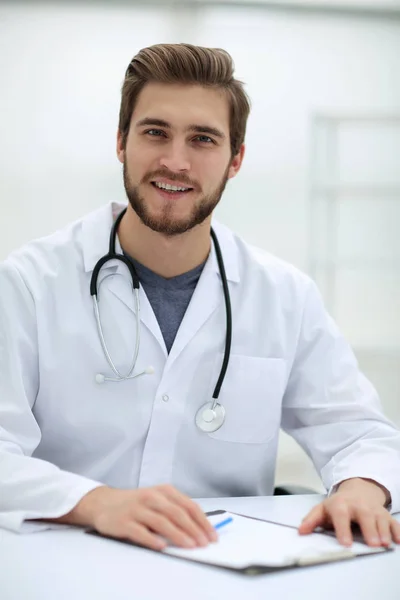 Amigable médico sentado detrás de un escritorio — Foto de Stock