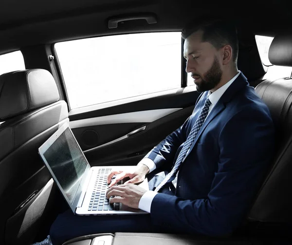 Бізнесмен використовує ноутбук на задньому сидінні автомобіля — стокове фото