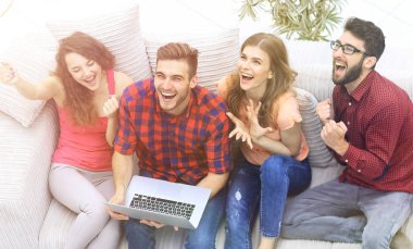 Bir grup arkadaş dizüstü bilgisayarda video izleyip gülüyorlar.