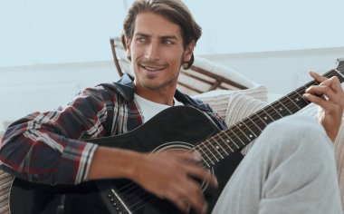 oturma odasında kanepede oturup gitar ile Modern adam.