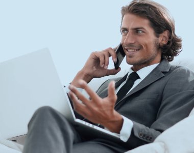 onun evinde sandalyede oturan smartphone cep telefonu ile konuşurken işadamı