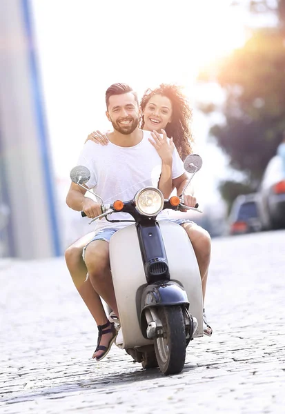 Happy young couple riding a scooter in the city on a sunny day — Stock Photo, Image
