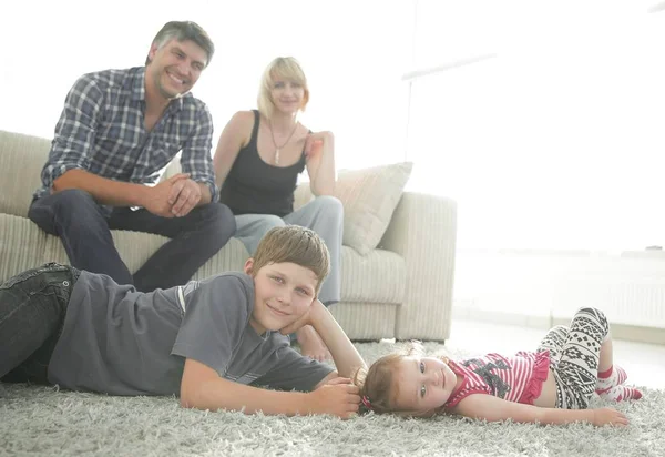 Portrait d'enfants tandis que les parents assis sur le canapé dans le salon roo — Photo