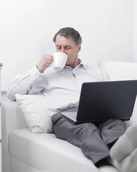 Geschäftsmann trinkt Tee und arbeitet im Hotelzimmer am Laptop — Stockfoto