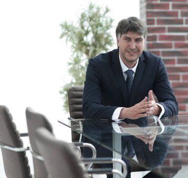 Bir boş konferans salonunda bir masada oturan proje yöneticisi