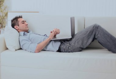 adam kanepede yatan dizüstü bilgisayar ile