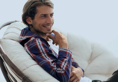 yakın çekim. gülümseyen adam büyük bir rahat sandalyede dinleniyor