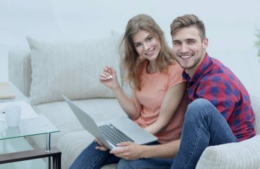 Dizüstü bilgisayarı olan iki öğrenci kanepede oturuyor.