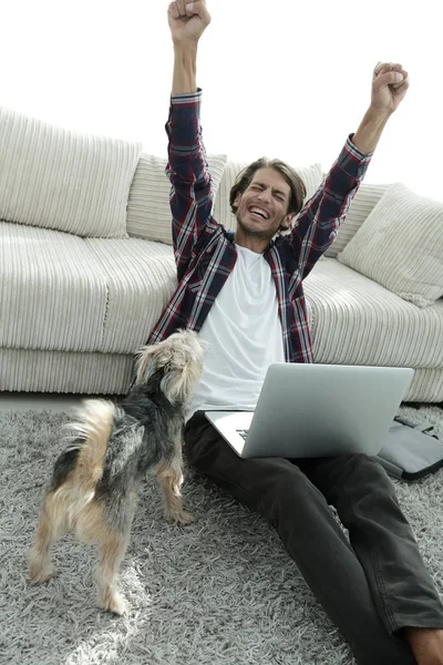 Glücklicher Kerl mit Laptop jubelt im geräumigen Wohnzimmer. — Stockfoto