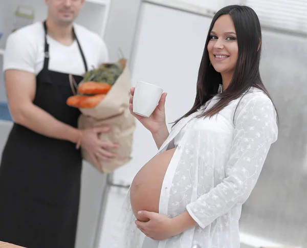 Happy pregnant couple of vegetarians in the kitchen. — Stock Photo, Image