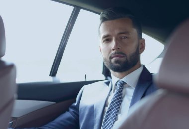 arabanın arka koltuğunda oturan yakışıklı sakallı işadamı