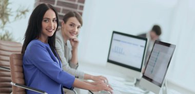 Kameraya bakarak ve oturma işyerinde gülümseyen genç kadın