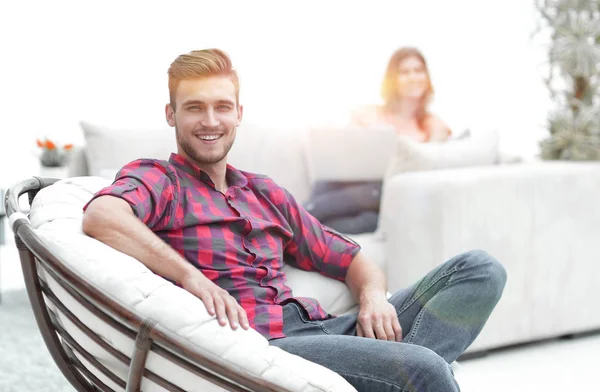 Sonriente joven macho sentado en una silla grande —  Fotos de Stock