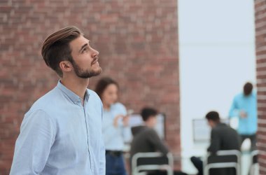 Genç işadamı ofiste çalışırken başka tarafa bakıyor..