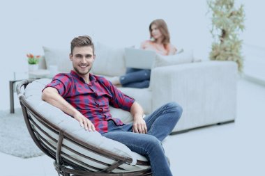 genç erkek büyük bir sandalyede oturuyor gülümseyen