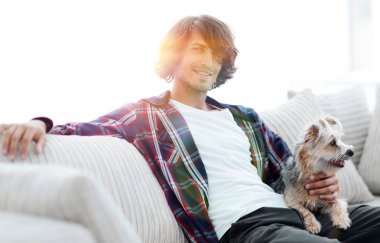 şık adam köpeğiyle kanepede oturan.