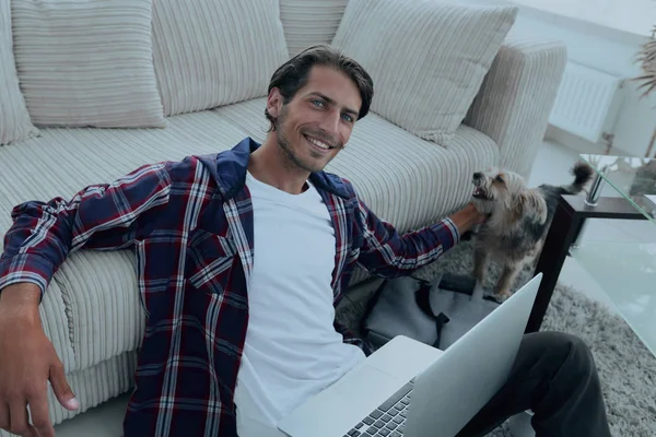 başarılı adam kanepede yakın katta oturan hayvanını okşayarak