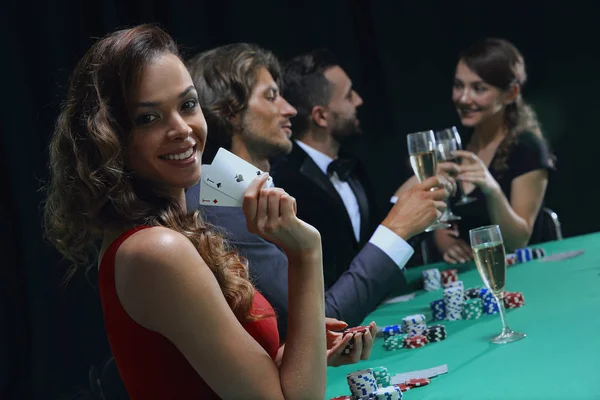 Young brunette woman playing poker on black background — Stock Photo, Image