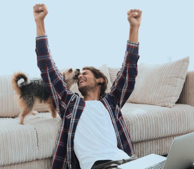 mutlu genç adam köpeğiyle oturma odasında exults