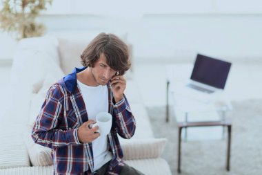 güzel bir fincan adamla bir dizüstü bilgisayar önünde oturur.