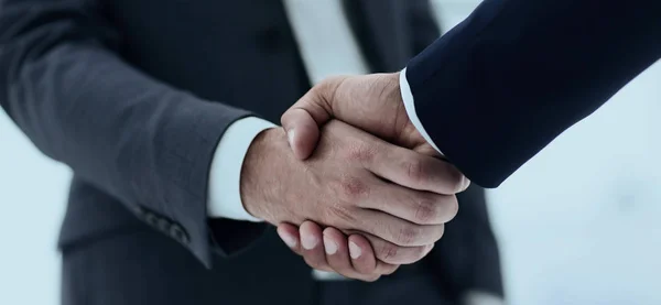 Primer plano de dos hombres jóvenes socio de negocios estrechan la mano —  Fotos de Stock