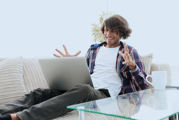 Χαρούμενος ο τύπος με το laptop που κάθεται στον καναπέ. έννοια της επιτυχίας — Φωτογραφία Αρχείου