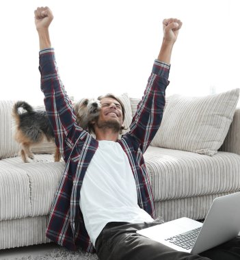 mutlu genç adam köpeğiyle oturma odasında exults