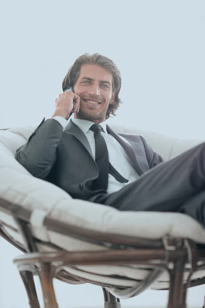 Biznes człowiek rozmawia na smartfonie, siedząc w wygodnym fotelu. — Zdjęcie stockowe