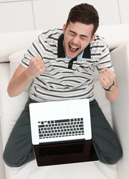 Vista de cima. jovem jubiloso com laptop sentado no sofá — Fotografia de Stock