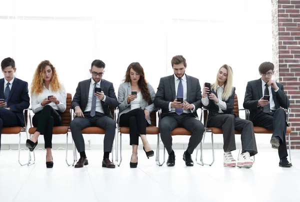 Empleados con smartphones sentados en el vestíbulo — Foto de Stock