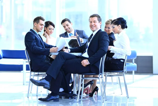 Affärsmannen och hans business-team med finansiella dokument sitter vid ett skrivbord i lobbyn på banken. — Stockfoto