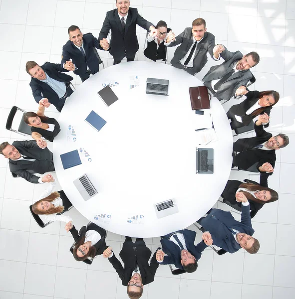 Groot business team zitten aan de ronde tafel en zijn handen omhoog — Stockfoto