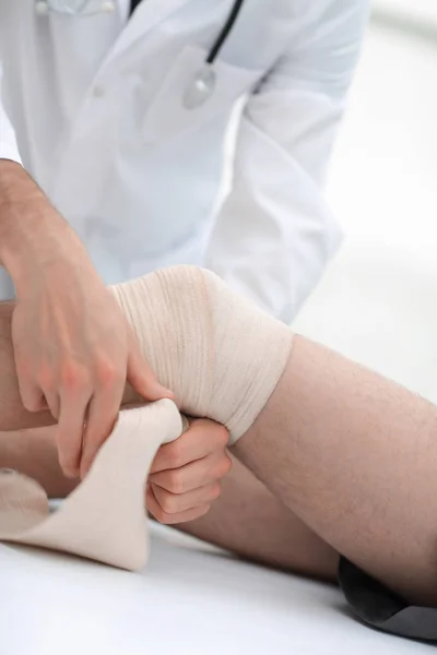 Arzt bandagiert Knie des Patienten — Stockfoto