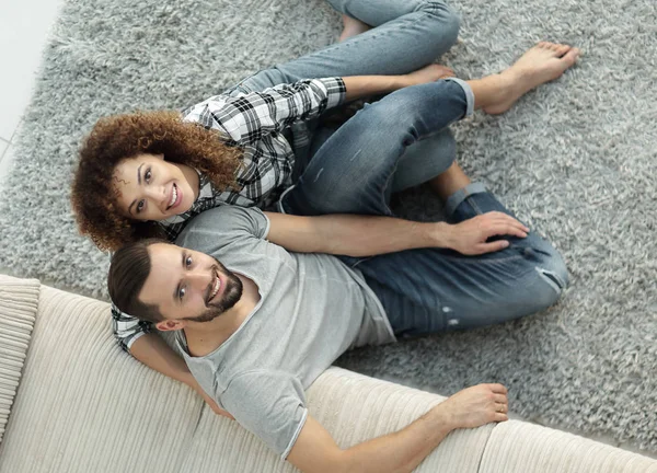 Pareja joven sentada en la alfombra en la nueva sala de estar — Foto de Stock