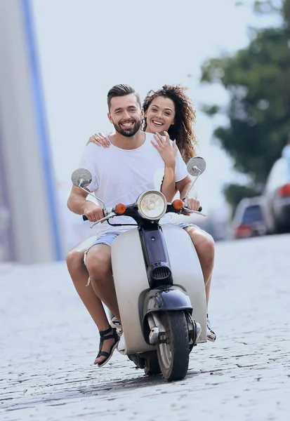 Happy young couple riding a scooter in the city on a sunny day — Stock Photo, Image