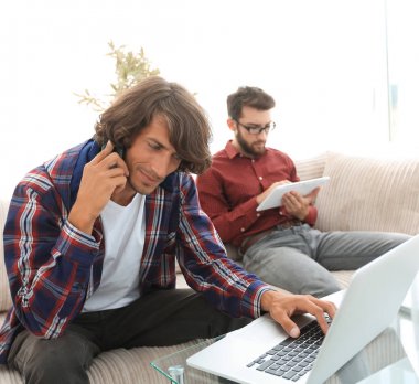 iki adam kanepede oturan, belgili tanımlık smartphone üzerinde konuşmak ve Internet üzerinde iletişim.