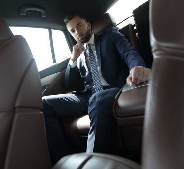 Bir arabanın arka koltuğunda oturan başarılı iş adamı