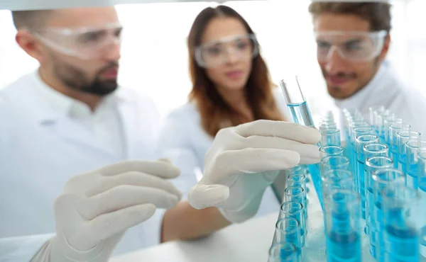 Obrázek na pozadí je skupina vědců studuje kapalinu do skleněné zkumavky. — Stock fotografie