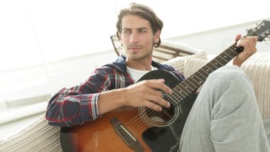 oturma odasında kanepede oturup gitar ile Modern adam.